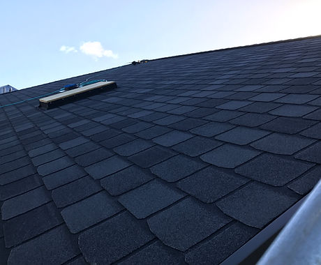 New dark shingle roof against a blue sky